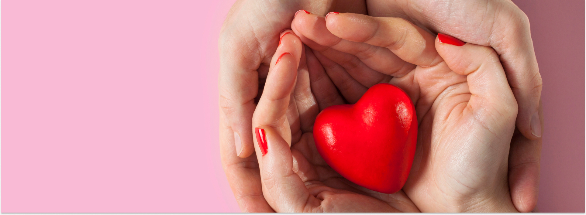 Manos una encima de la otra con un corazón de juguete en el medio