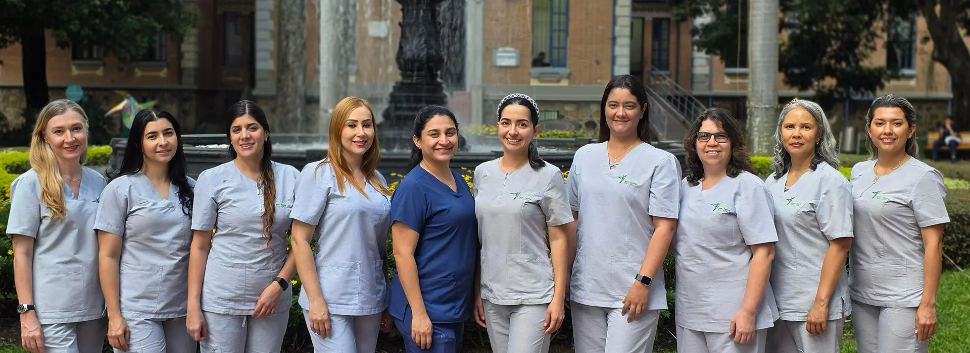 Foto de muchas mujeres empleadas de Hospital San vicente con sus uniformes y un fondo del hospital con una fuente de agua